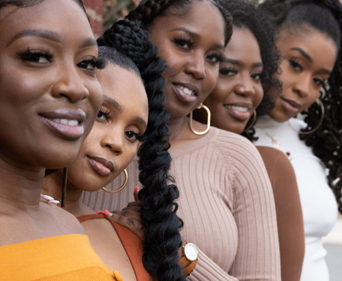 A group of six women standing in a line, showcasing a variety of warm-toned ribbed knit outfits in mustard yellow, rust orange, beige, and brown.